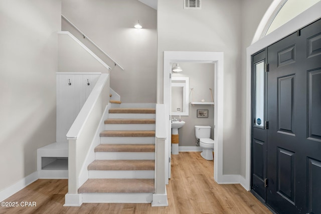 foyer entrance featuring visible vents, stairway, baseboards, and wood finished floors