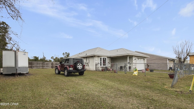 rear view of house featuring a yard, an attached garage, and fence private yard