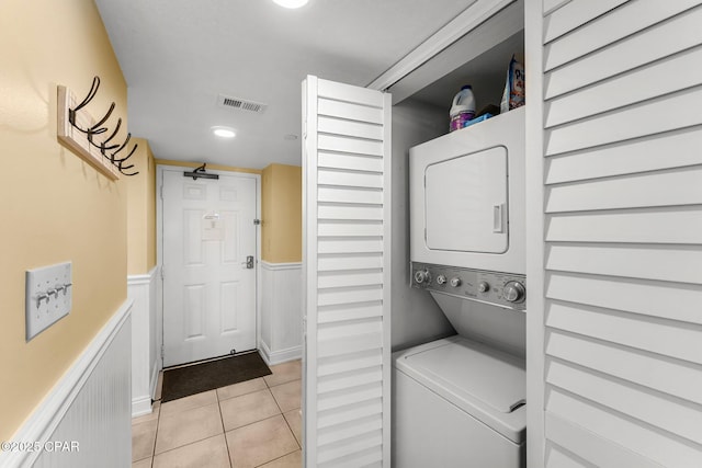 washroom with light tile patterned floors, laundry area, visible vents, wainscoting, and stacked washing maching and dryer