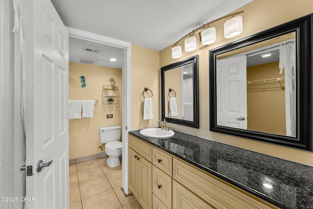 bathroom featuring visible vents, a spacious closet, toilet, vanity, and tile patterned flooring