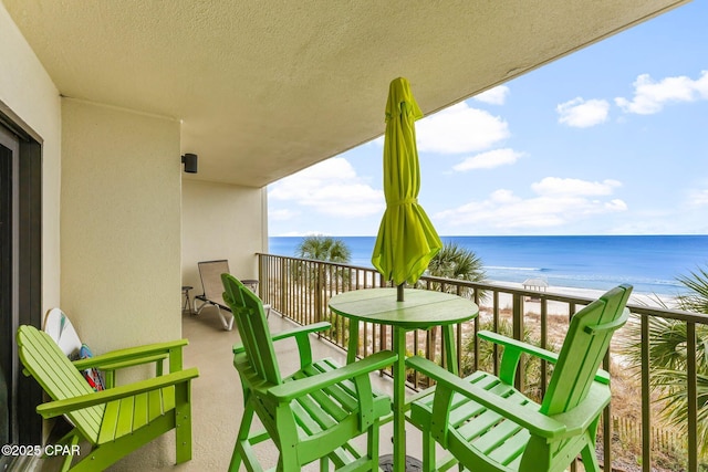 balcony featuring a view of the beach and a water view