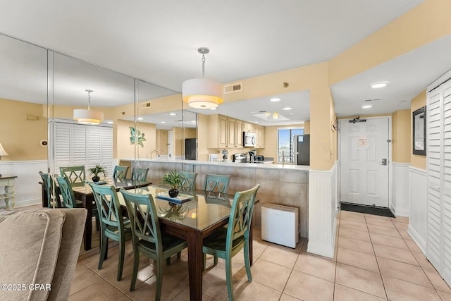 dining space featuring light tile patterned floors, wainscoting, visible vents, and recessed lighting