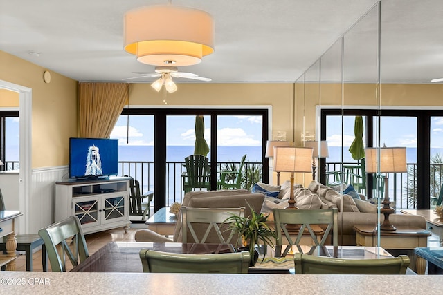 living room with a ceiling fan and a wainscoted wall