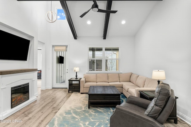 living room featuring light wood-style flooring, a ceiling fan, baseboards, recessed lighting, and vaulted ceiling with beams