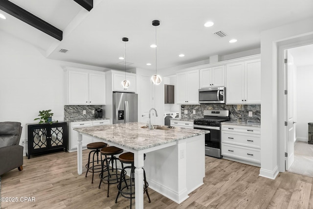 kitchen with appliances with stainless steel finishes, a breakfast bar, a sink, backsplash, and visible vents