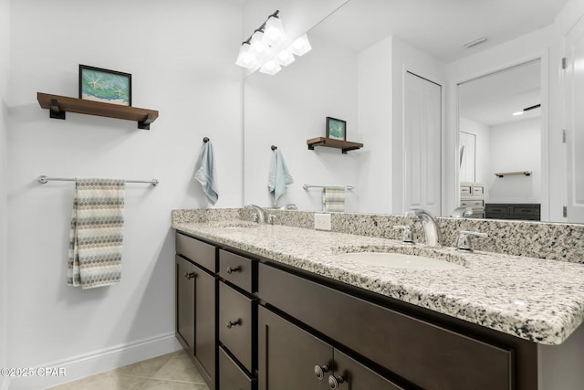 bathroom with a sink, baseboards, tile patterned flooring, and double vanity