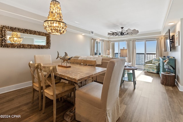 dining space with a raised ceiling, baseboards, and wood finished floors