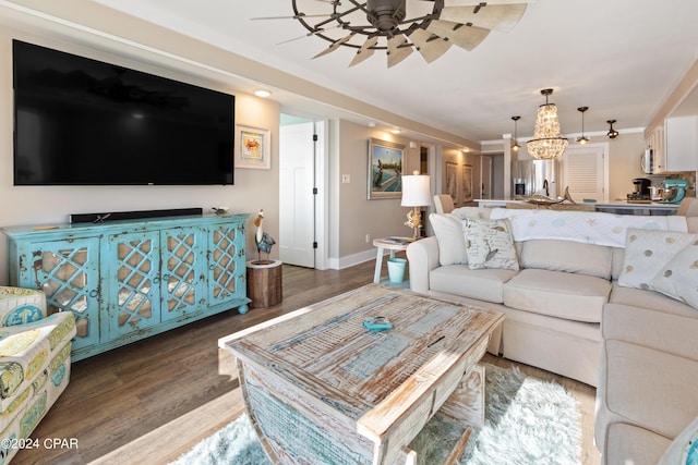 living room with baseboards, wood finished floors, and ceiling fan with notable chandelier