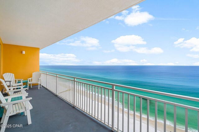 balcony featuring a view of the beach and a water view