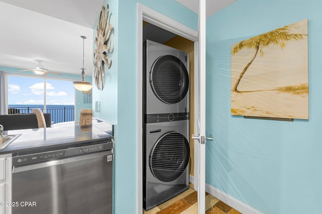 laundry area with baseboards, light wood-type flooring, laundry area, stacked washer and clothes dryer, and a sink