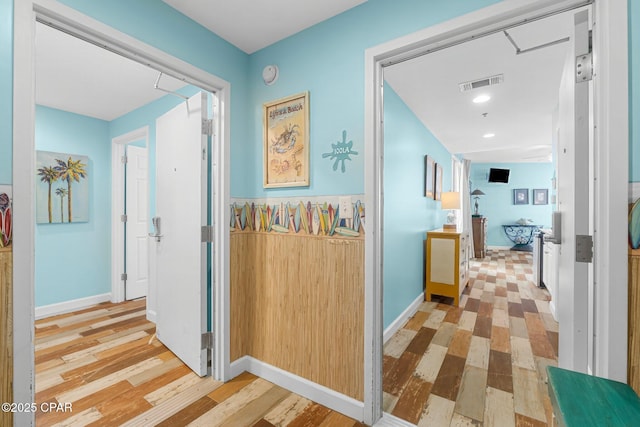 hallway with visible vents, baseboards, and wood finished floors