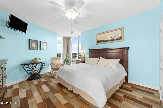 bedroom with a wall of windows, baseboards, wood finished floors, and a ceiling fan