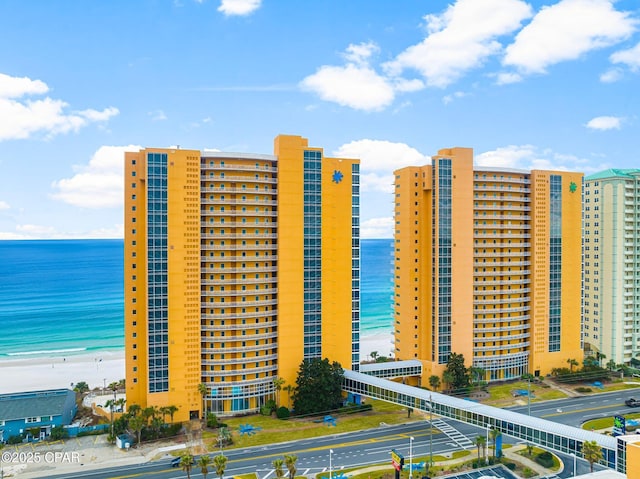 view of property with a beach view, a water view, and uncovered parking