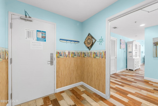 corridor with visible vents, baseboards, and wood finished floors