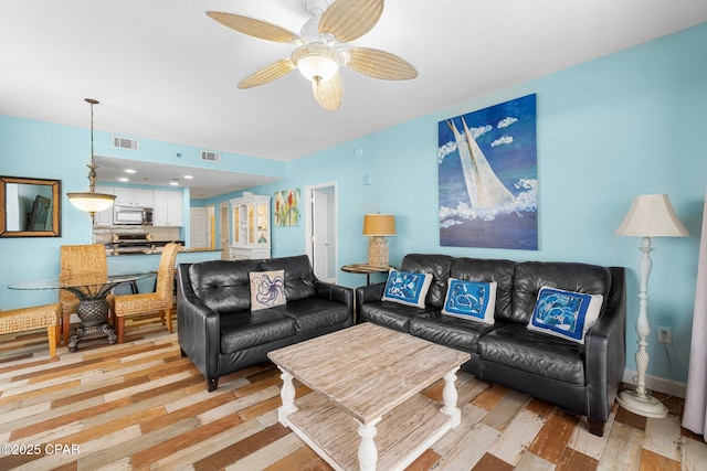 living room with light wood finished floors, visible vents, and a ceiling fan