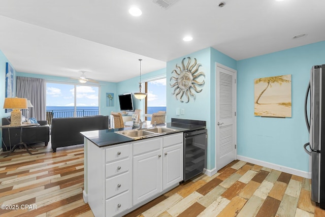 kitchen featuring beverage cooler, a sink, dark countertops, freestanding refrigerator, and a peninsula