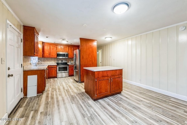 kitchen featuring a sink, light wood-style floors, light countertops, appliances with stainless steel finishes, and tasteful backsplash