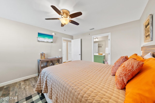 bedroom featuring ceiling fan, wood finished floors, visible vents, baseboards, and ensuite bath