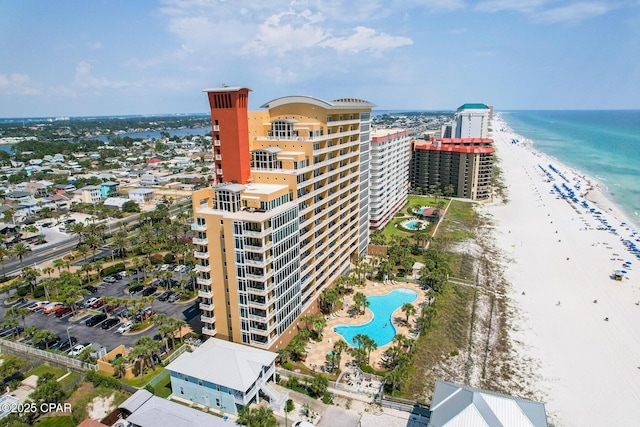 drone / aerial view featuring a water view, a city view, and a view of the beach