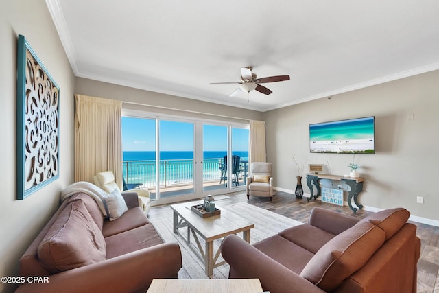 living area featuring ornamental molding, a ceiling fan, baseboards, and wood finished floors