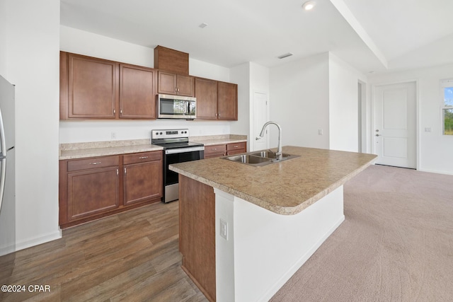 kitchen featuring stainless steel appliances, recessed lighting, light countertops, a sink, and an island with sink