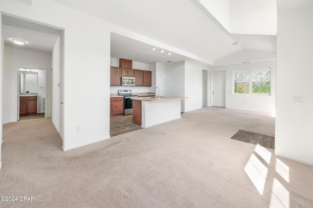 kitchen featuring open floor plan, appliances with stainless steel finishes, brown cabinetry, and light carpet