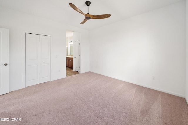 unfurnished bedroom featuring baseboards, a ceiling fan, light colored carpet, ensuite bathroom, and a closet