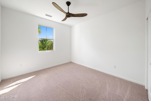 carpeted spare room with visible vents, ceiling fan, and baseboards