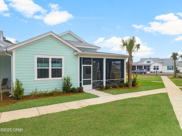 view of front facade with a sunroom, a front lawn, and roof with shingles