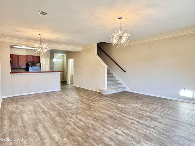 unfurnished living room with visible vents, stairway, wood finished floors, crown molding, and a notable chandelier