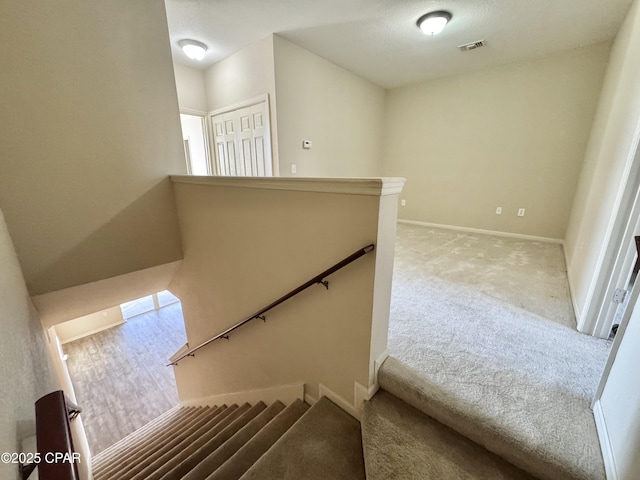 stairs featuring baseboards, visible vents, and carpet flooring