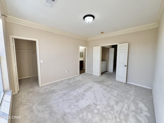 unfurnished bedroom featuring crown molding, washer and clothes dryer, a closet, visible vents, and a spacious closet