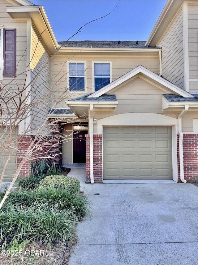 view of front of property featuring a garage, driveway, and brick siding