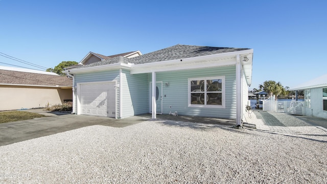 view of front facade featuring a garage, gravel driveway, roof with shingles, and fence