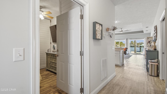 corridor featuring light wood-style floors, visible vents, and baseboards