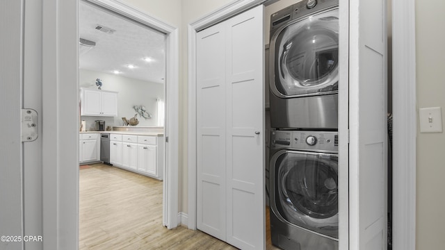 laundry area featuring visible vents, laundry area, stacked washer and dryer, and light wood-style flooring