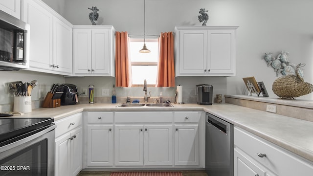 kitchen featuring white cabinets, appliances with stainless steel finishes, light countertops, and a sink