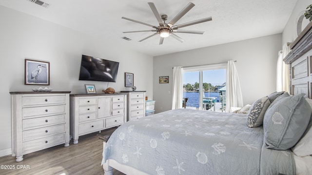 bedroom with access to outside, light wood finished floors, visible vents, and a ceiling fan