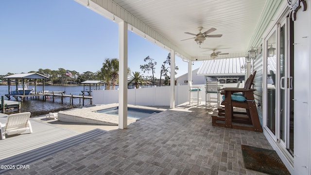 view of patio with boat lift, an in ground hot tub, a water view, fence, and a boat dock