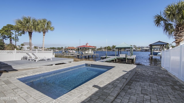 view of pool with a boat dock, boat lift, a water view, fence, and a gazebo