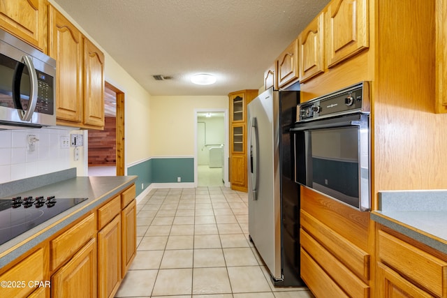 kitchen featuring tasteful backsplash, visible vents, light tile patterned flooring, a textured ceiling, and black appliances