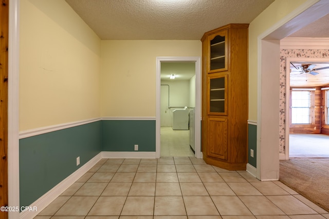 spare room with light tile patterned floors, a ceiling fan, a textured ceiling, and light colored carpet