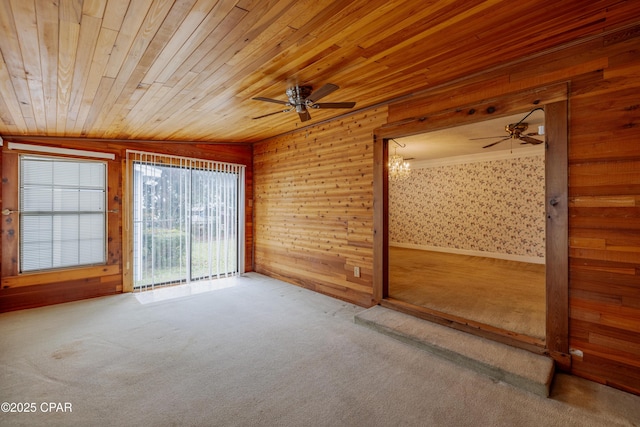 carpeted empty room with wood ceiling, ceiling fan, and wood walls