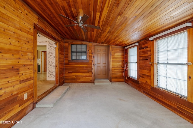 empty room featuring wooden ceiling, wood walls, ceiling fan, and light carpet