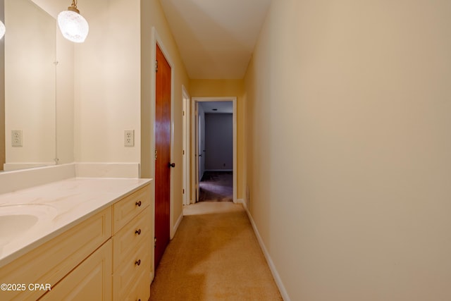 hallway featuring baseboards and light colored carpet