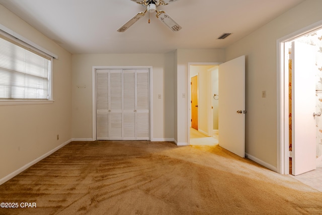 unfurnished bedroom featuring light colored carpet, a closet, visible vents, and baseboards