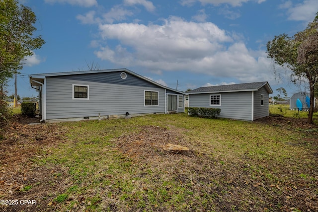 rear view of property with crawl space and a lawn