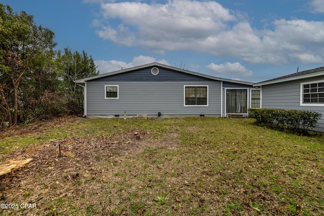 rear view of property with crawl space and a lawn