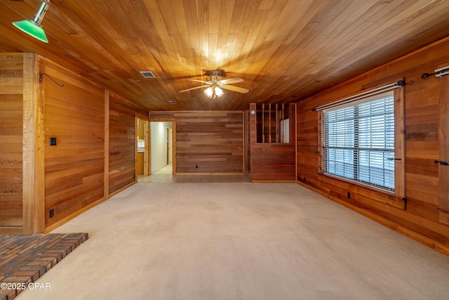 spare room with carpet floors, wooden ceiling, visible vents, and wood walls