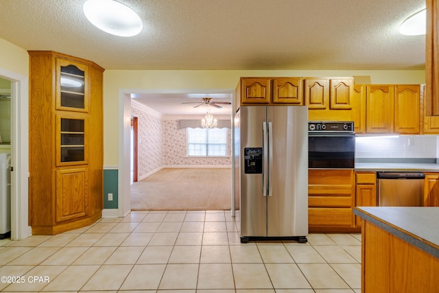 kitchen with appliances with stainless steel finishes, light tile patterned floors, a textured ceiling, and wallpapered walls